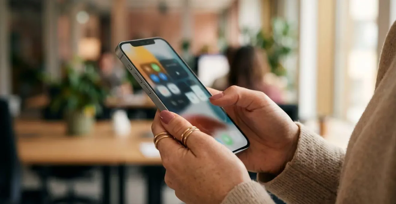 Main tenant un smartphone montrant une interface floue avec des boutons de choix symboliques pour les cookies