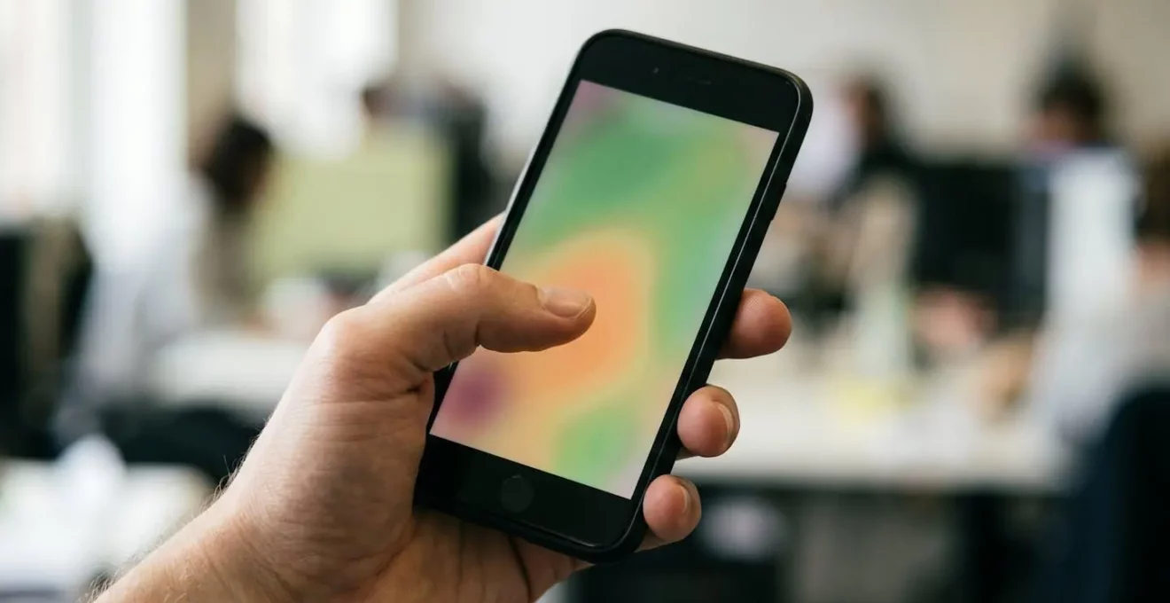 Main tenant un smartphone dans une position naturelle montrant les zones accessibles du pouce