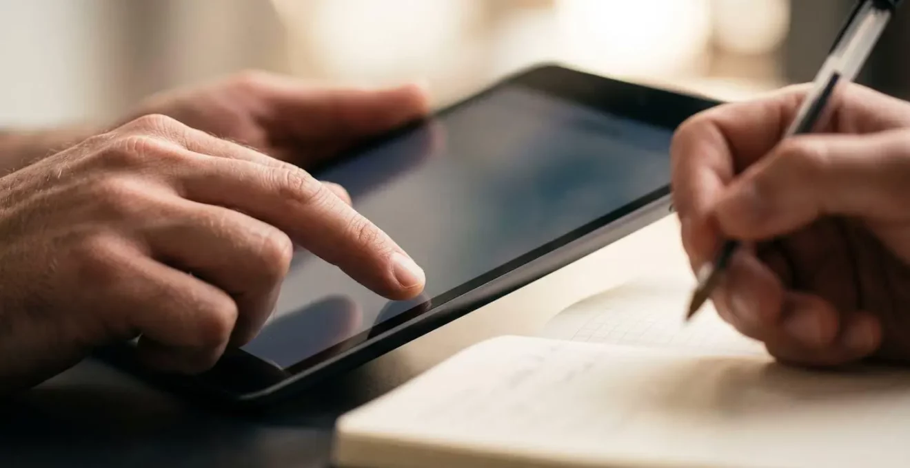 Observateur prenant des notes pendant qu'une personne teste naturellement une interface sur tablette